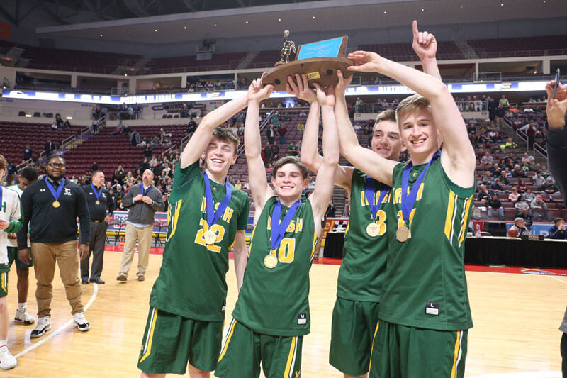 boys basketball players holding trophy overhead