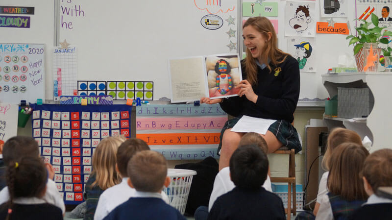 female student reading to elementary students