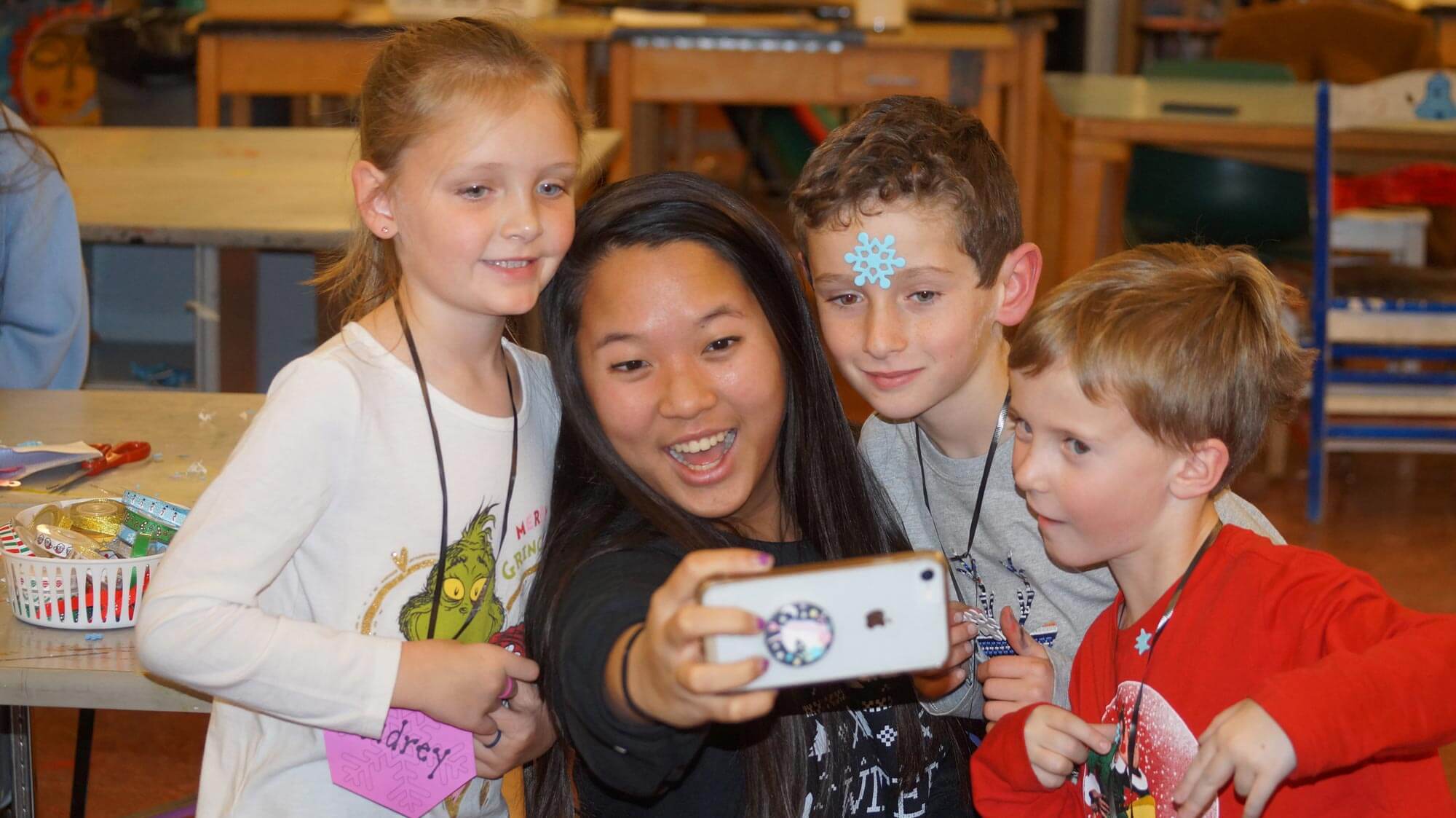 hs girl taking selfie with elementary students