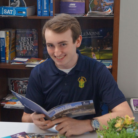 male student reading college brochures