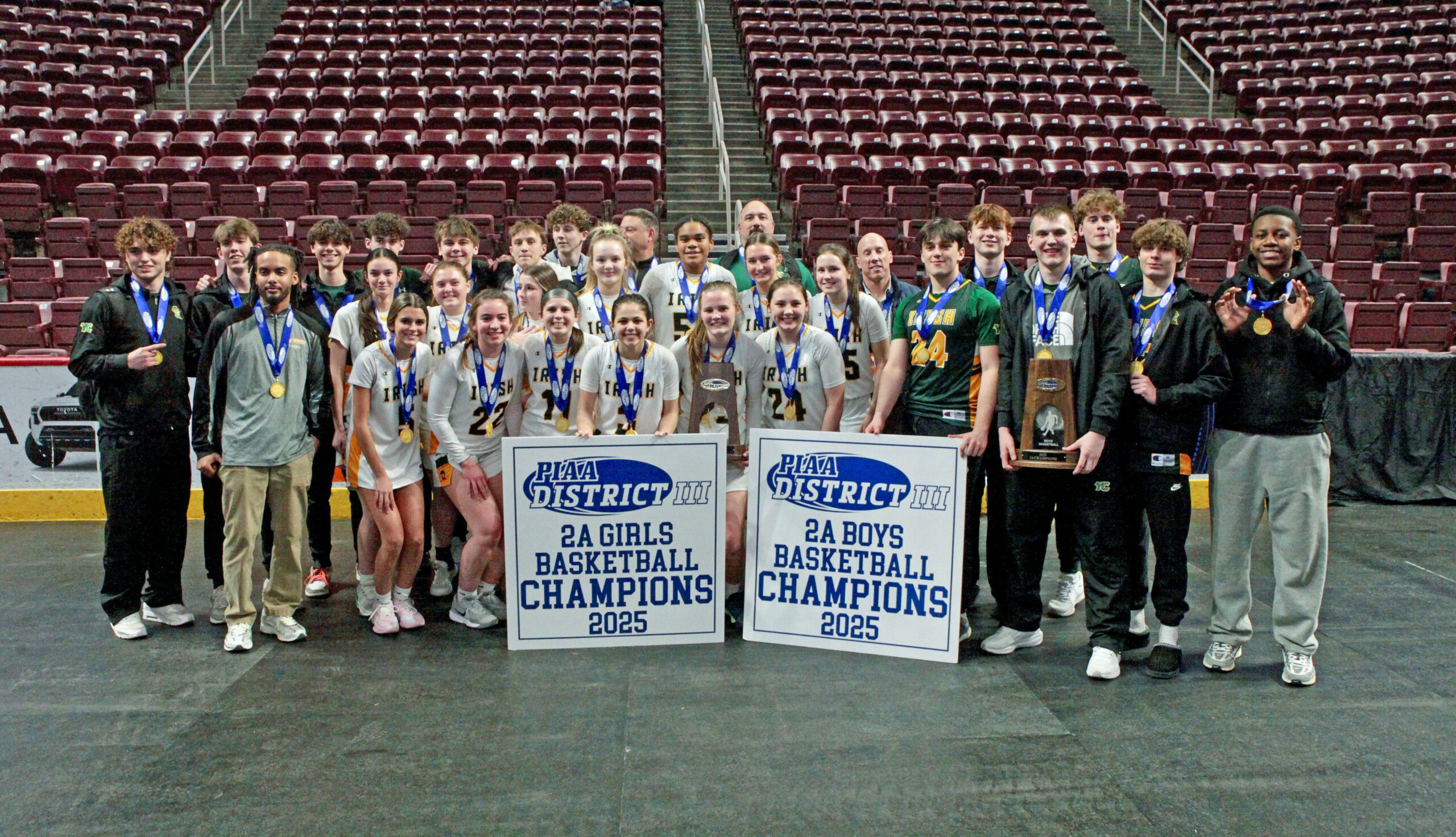 boys and girls basketball teams standing behind championship banners