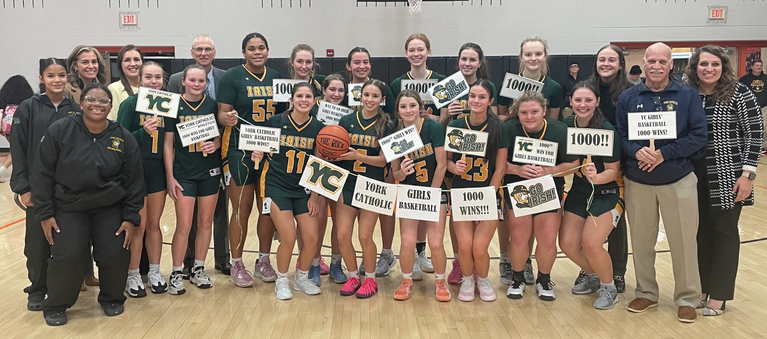 girls basketball team holding signs for 1000 wins