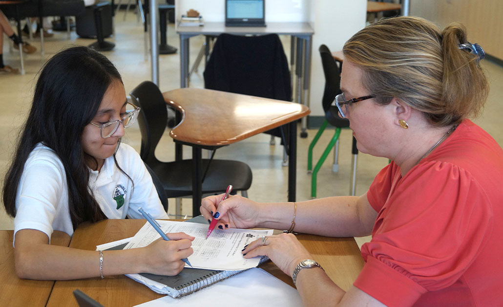 Teacher giving instruction to student at desk in classroom