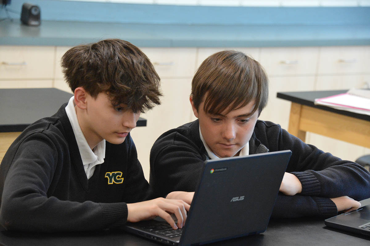 2 YC students in front of laptop on desk doing schoolwork