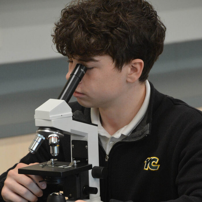 student looking through microscope during science class