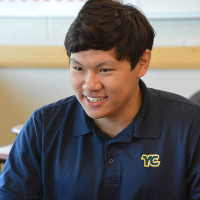 smiling YC student sitting at desk while smiling in front of computer
